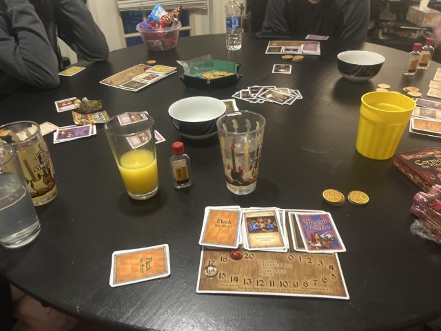Image of several people playing a board game and drinking.
